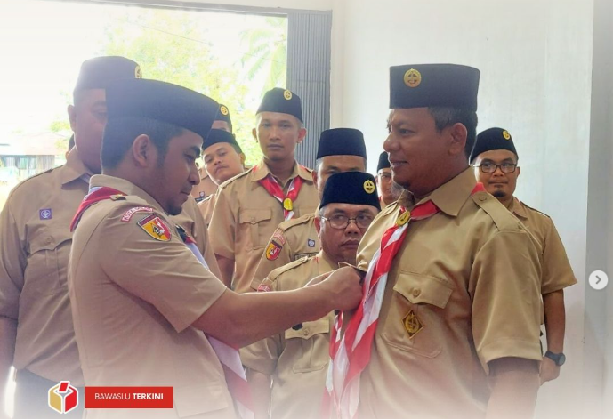 Ketua Kwarcab Kota Solok (kiri) menyematkan tanda jabatan kepada Ketua Bawaslu Kota Solok (kanan) sebagai simbolis pelantikan kepengurusan Satuan Karya (Saka) Pramuka Adhyasta Pemilu Kota Solok Masa Bakti 2025–2030, pada Selasa (11/11/2025) di Kantor Bawaslu Kota Solok.